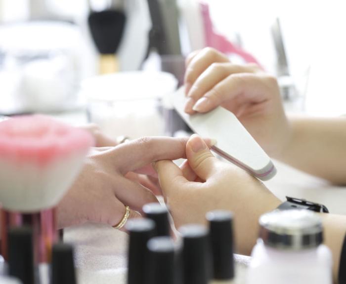 Woman at a nail salon getting her nails filed